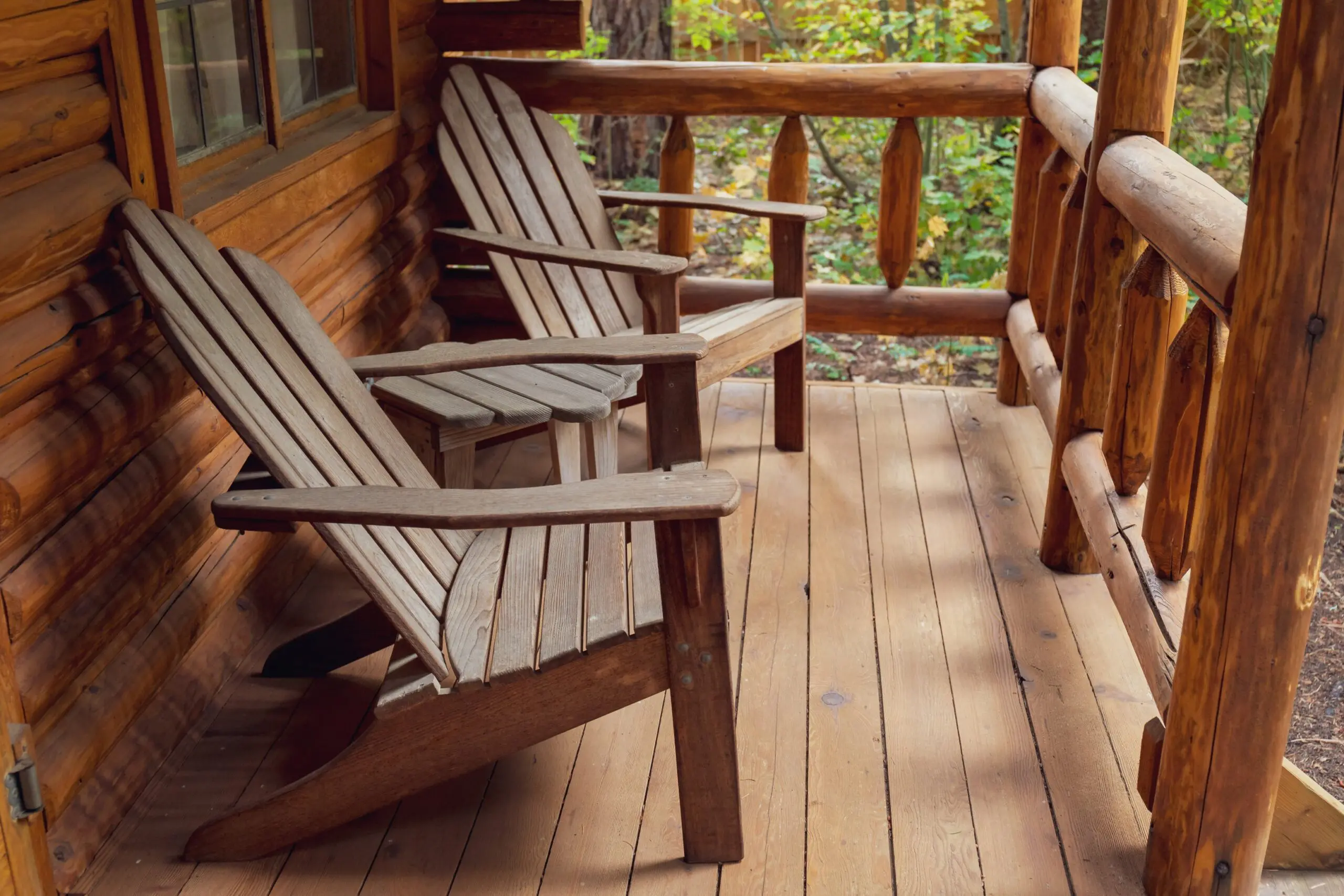 Wooden chairs on a rustic cabin porch.