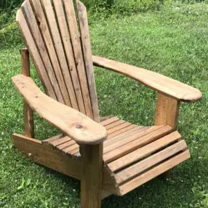 Wooden Adirondack chair on green grass outdoors.