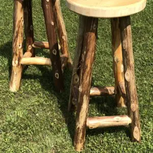 Rustic wooden stools with natural bark finish on green grass.