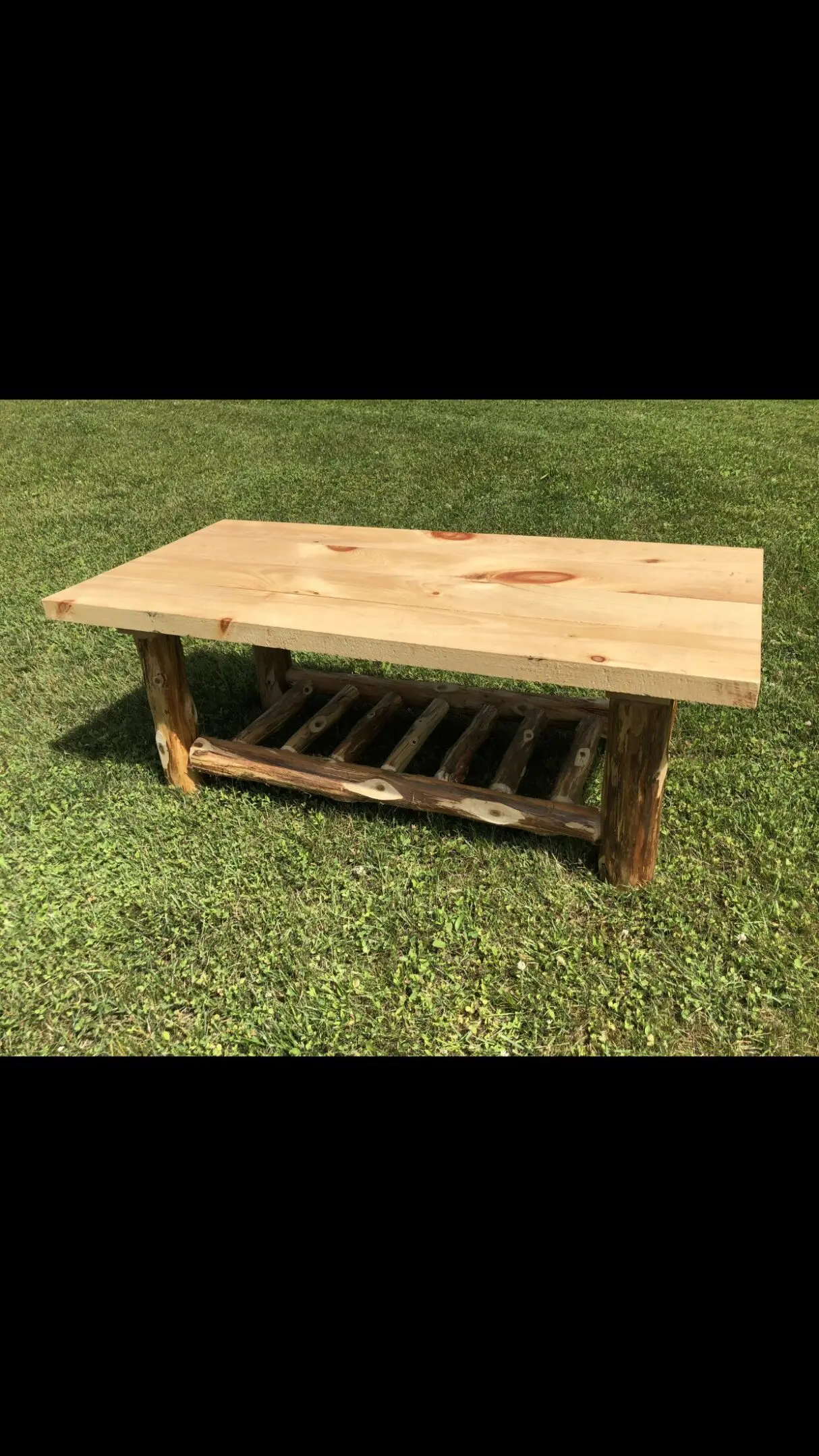 Rustic wooden coffee table with a slatted lower shelf on grass.