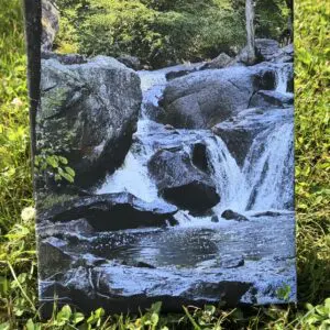 A flowing waterfall over rocks surrounded by greenery.