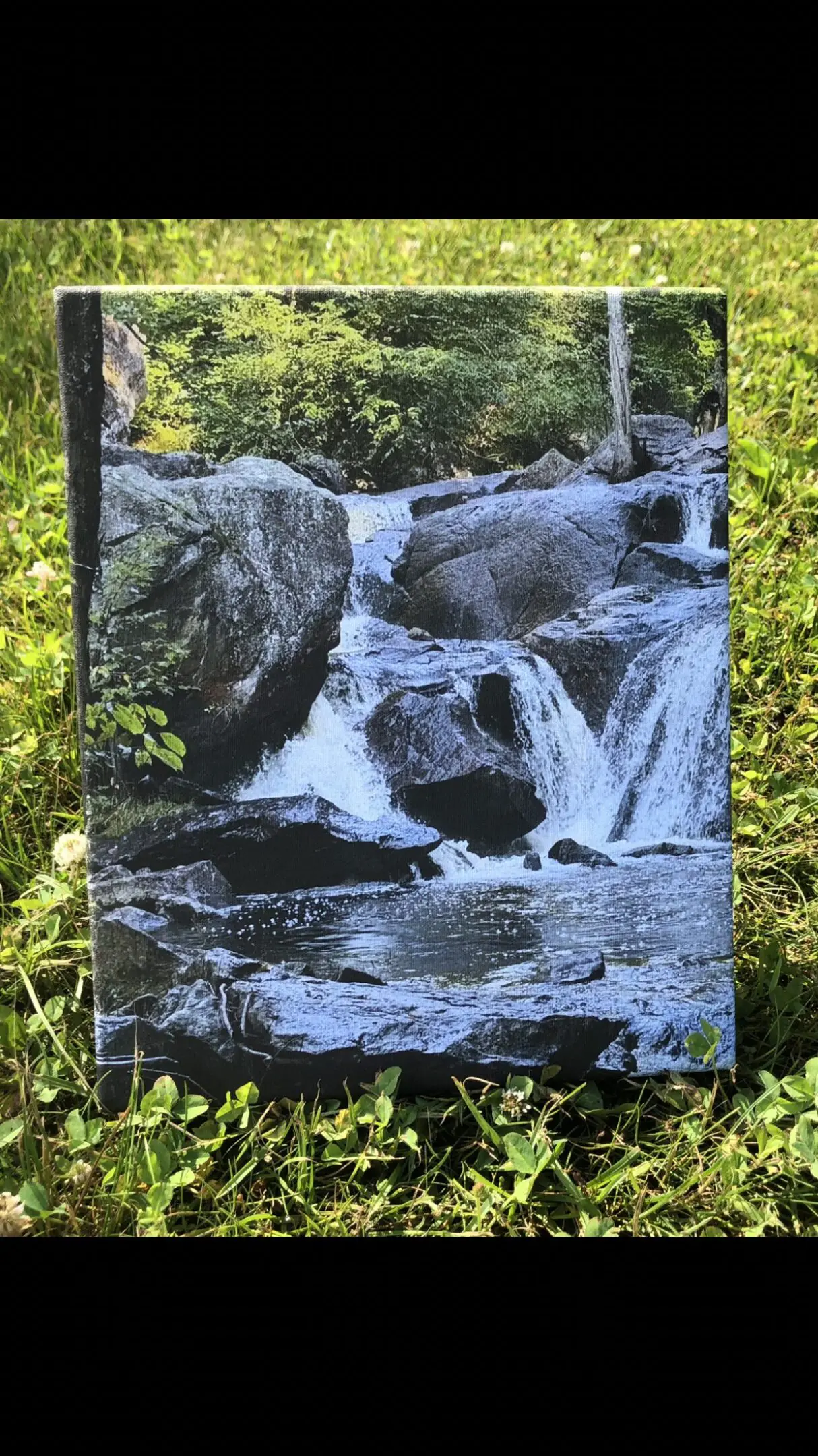 A flowing waterfall over rocks surrounded by greenery.
