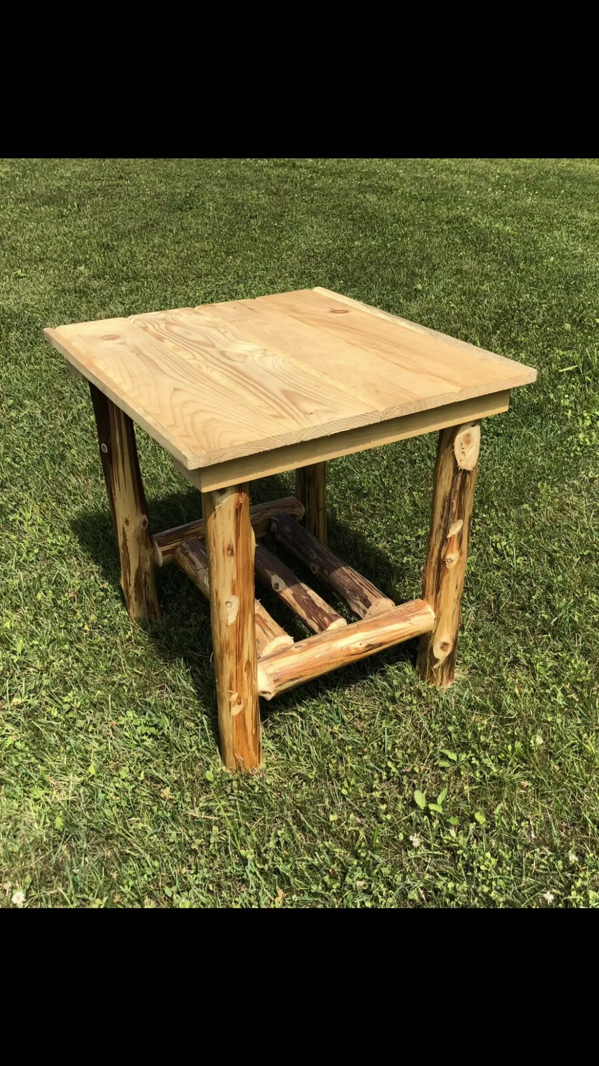 Rustic wooden side table with log legs on grass.