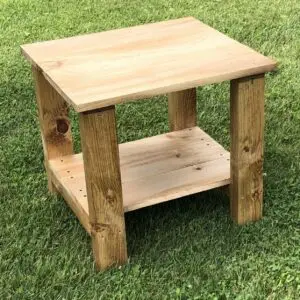 A rustic wooden side table with a lower shelf on grass.