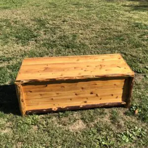 Wooden storage chest with a hinged lid on grass.