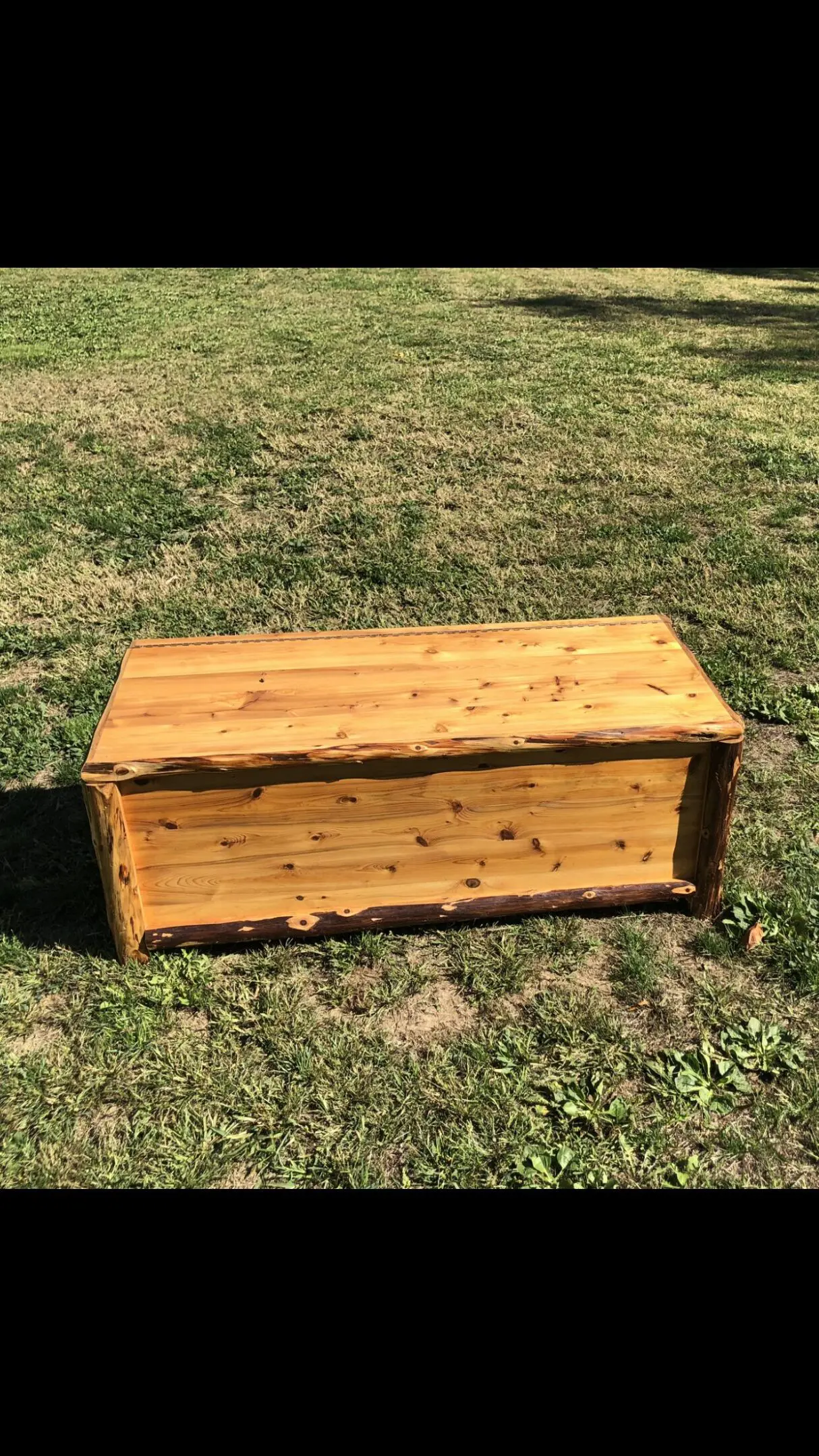 Wooden storage chest with a hinged lid on grass.