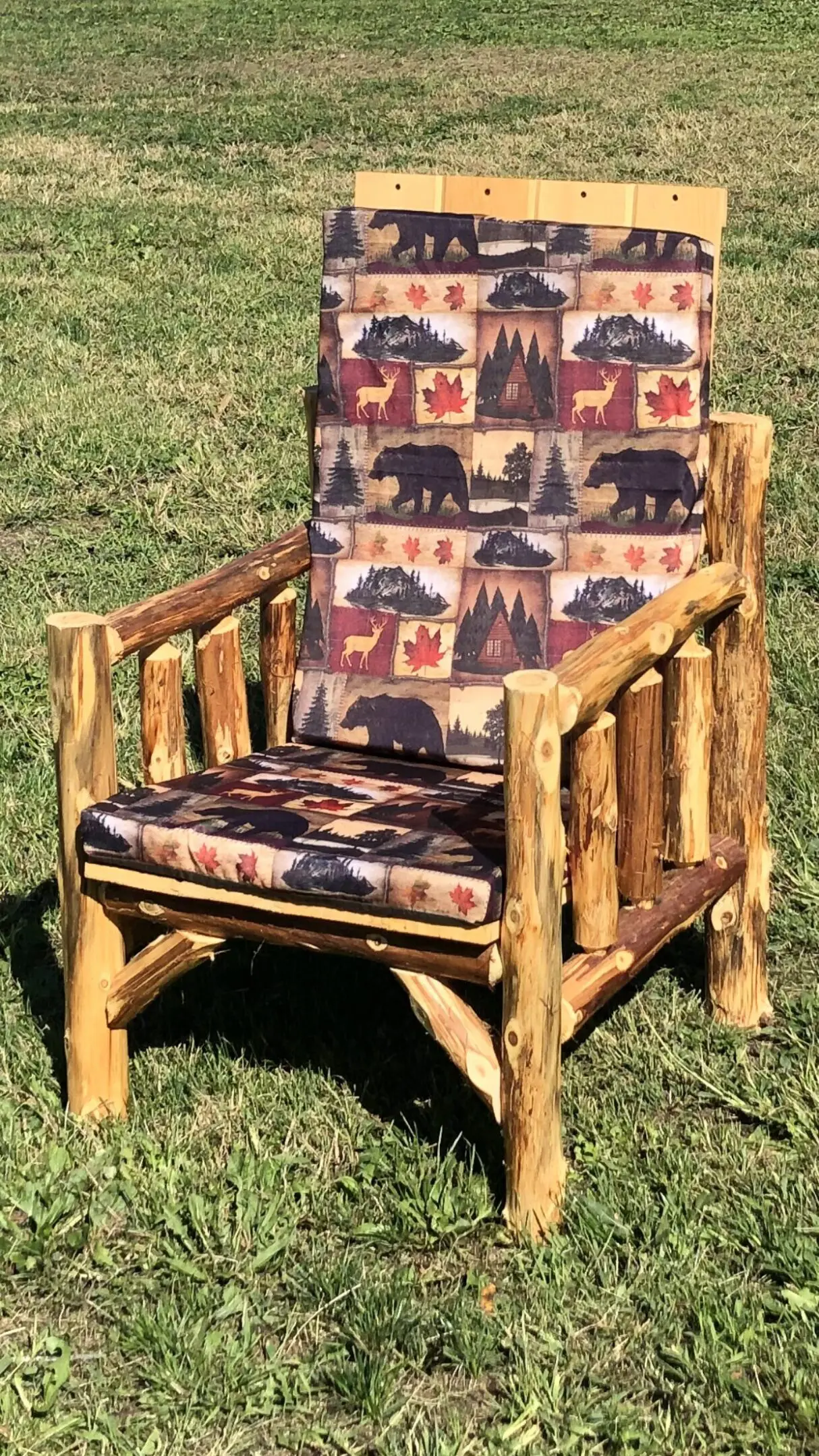 Rustic wooden chair with bear-themed cushions on grass.