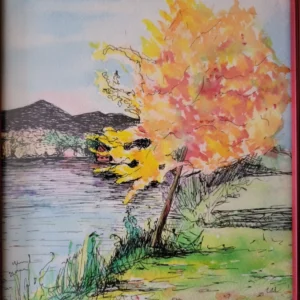 A vibrant autumn tree by a lakeside with mountains in the background.
