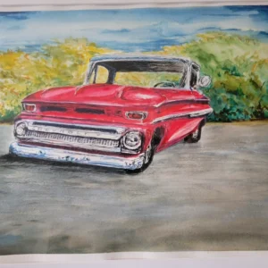 A vintage red car parked on a road with greenery in the background.