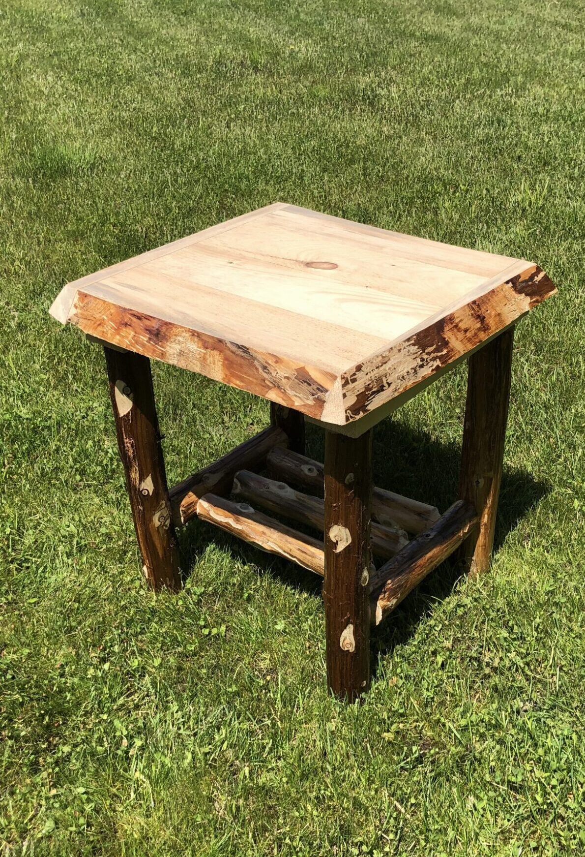 Rustic wooden side table with natural edges on grass.