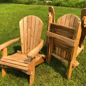 Wooden Adirondack chairs on a grassy lawn in sunlight.
